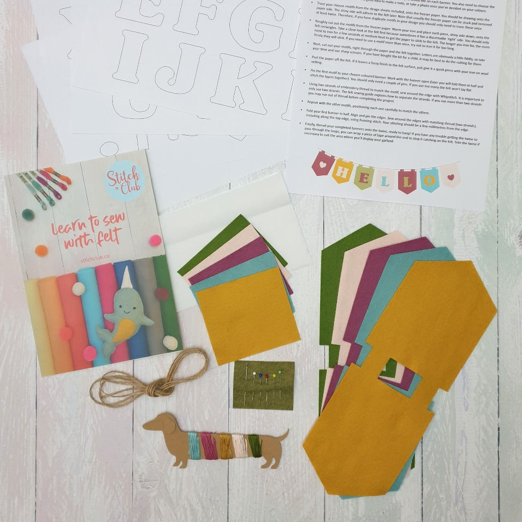 A photo of the contents of a sewing kit, featuring felt banners, threads and pins