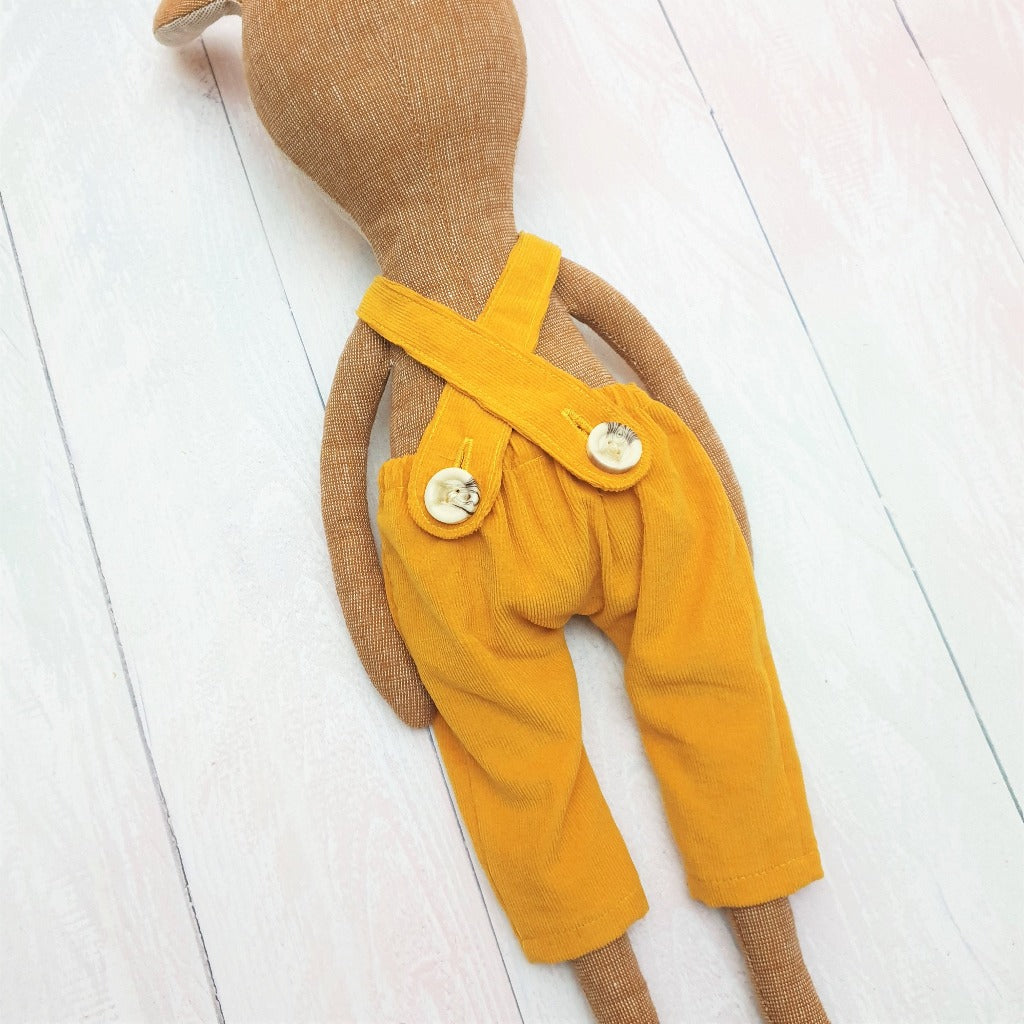 Detail of a Deer soft toy, handsewn, wearing yellow corduroy dungarees with a button back