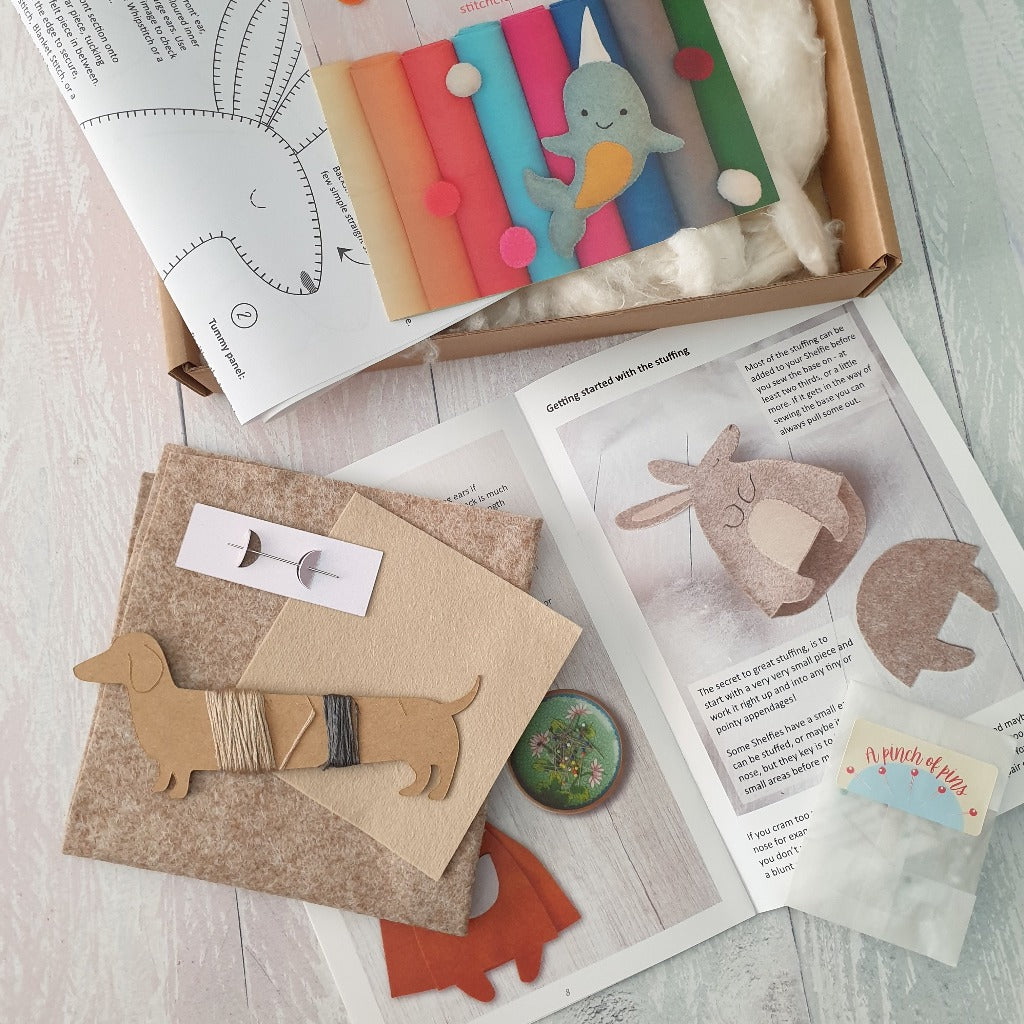 sewing supplies scattered on a surface, with colourful sewing guides, felt and threads