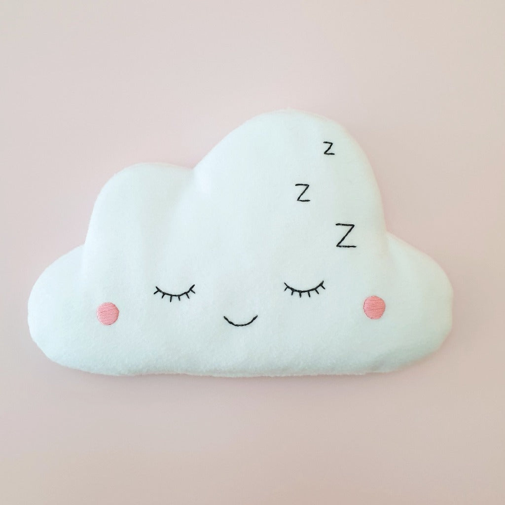 A fluffy white cloud sewn from fleece has an embroidered sleepy face. It is filled with rice and lavender, to be warmed in the microwave.