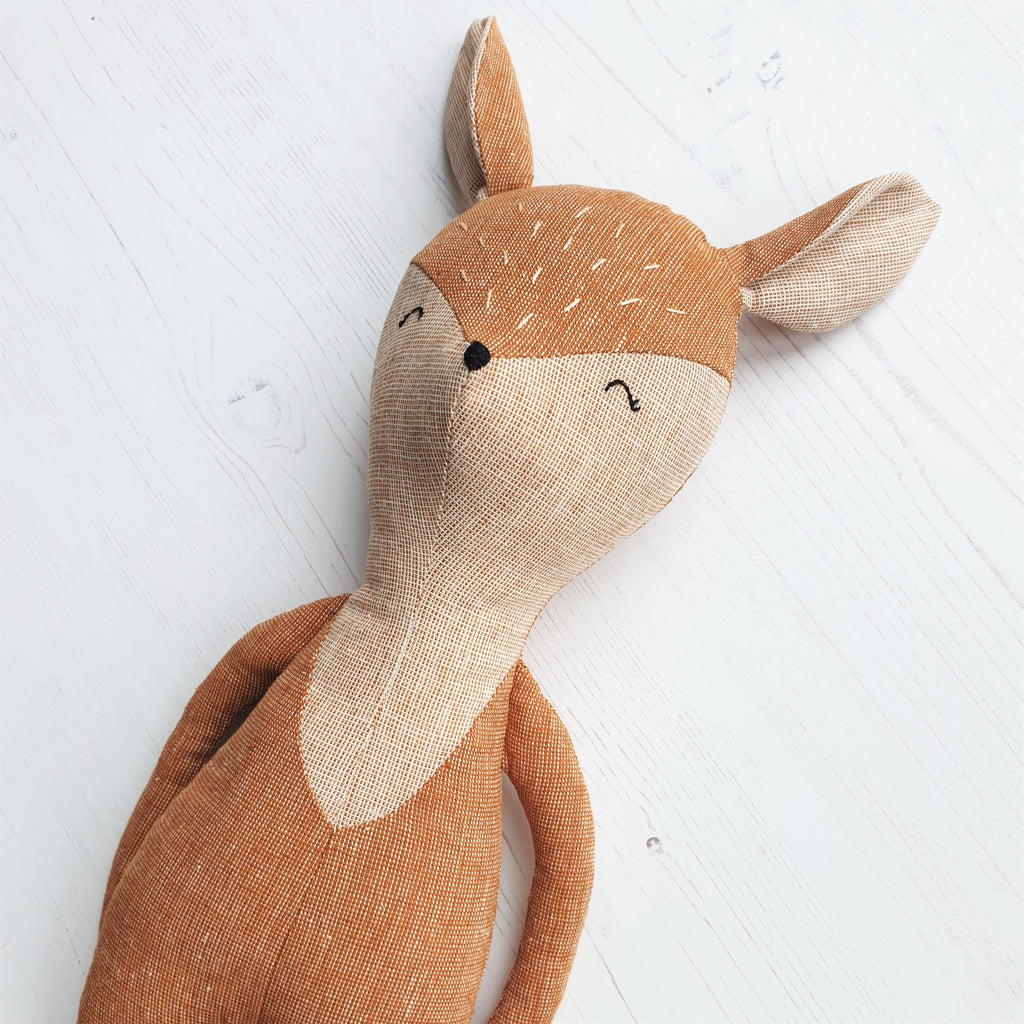 A close up of a vintage style handmade toy deer, featuring home-spun essex linen fabrics.
